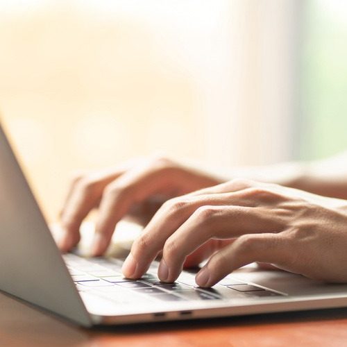 HandTyping Close-up of a person's hands typing on a laptop keyboard with natural light in the background.